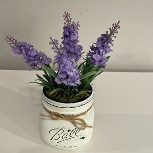 Distressed glass jar with artificial purple flowers